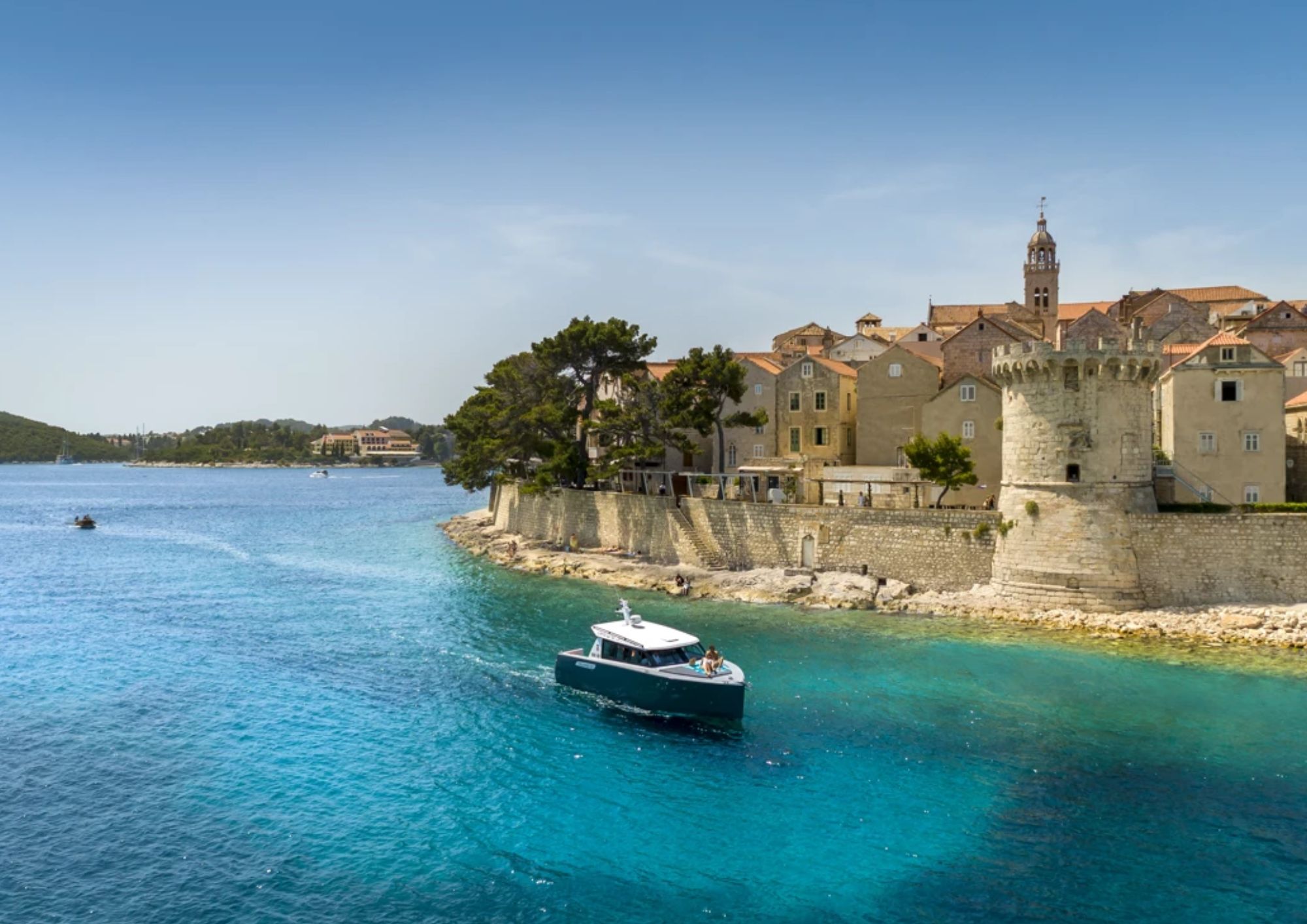 Aminess Younique Korčula Heritage Hotel old town walls and a boat on the turquoise sea
