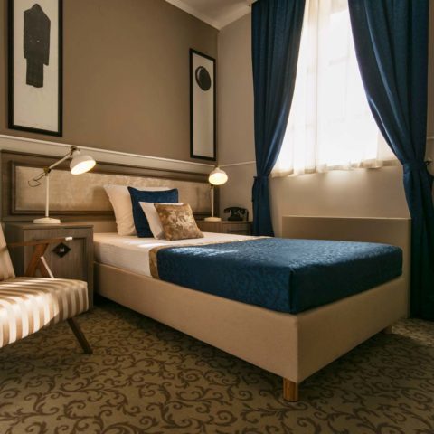 Hotel Jagerhorn bedroom with blue bed throw, dark curtains and parquet floor