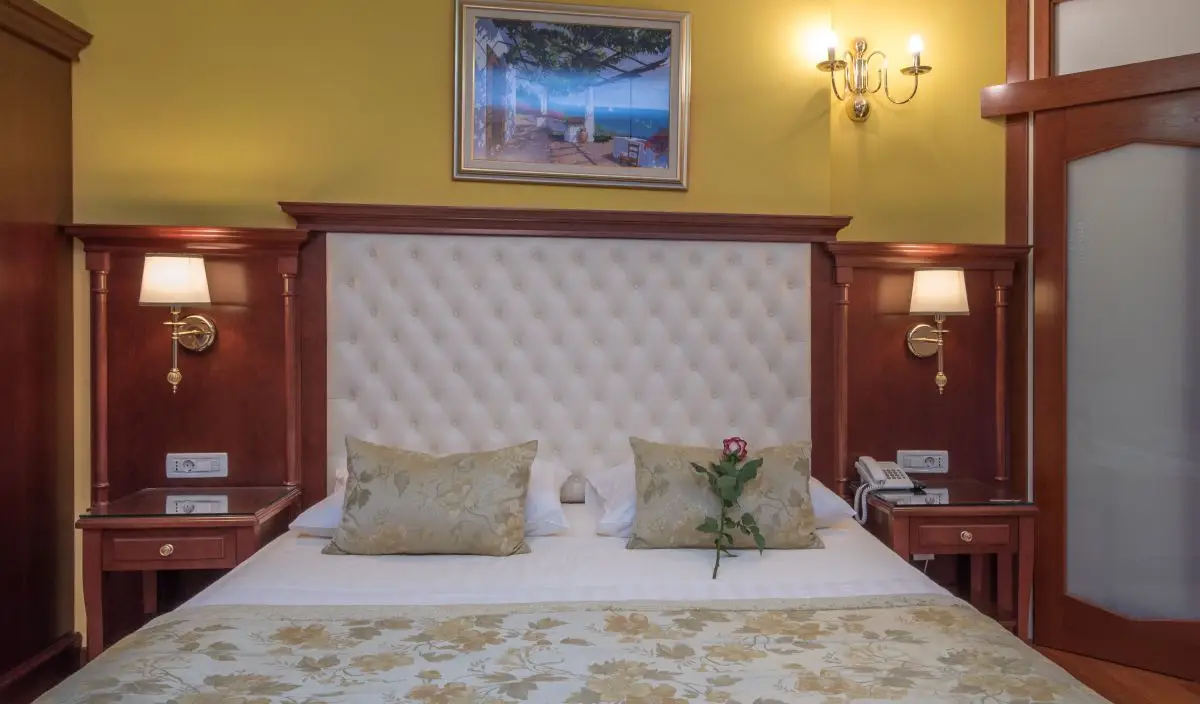 Trogir Palace bed with tufted headboard against yellow walls