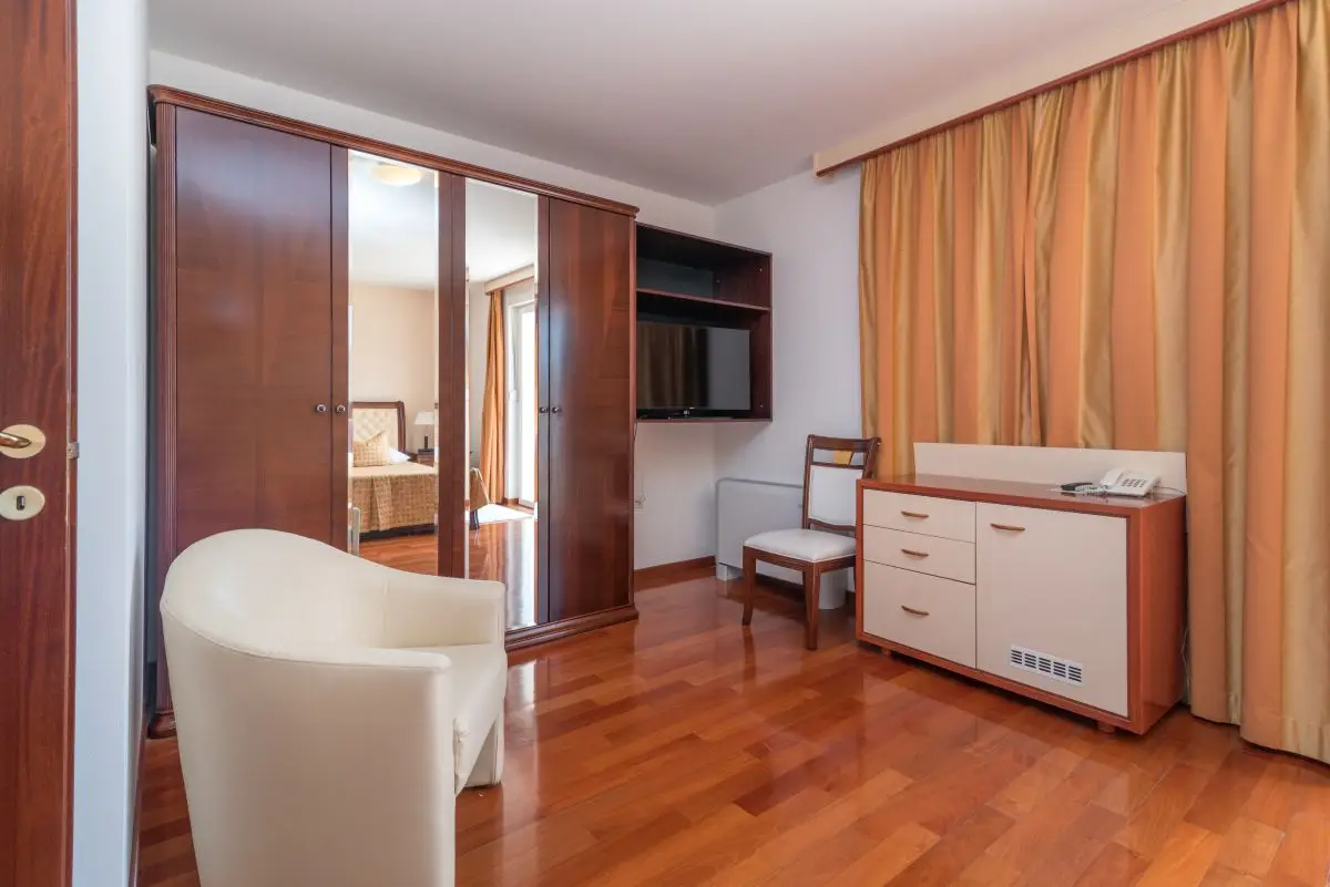 Trogir Palace room with white tub chair and wooden wardrobe