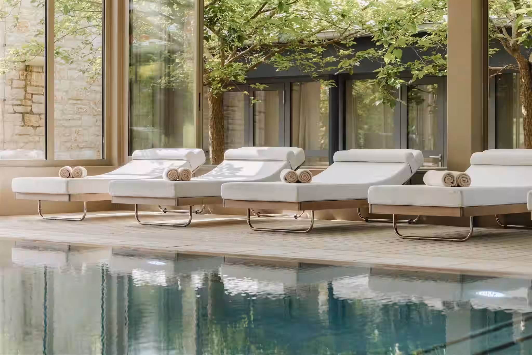 Meneghetti pool with white loungers beneath a pergola