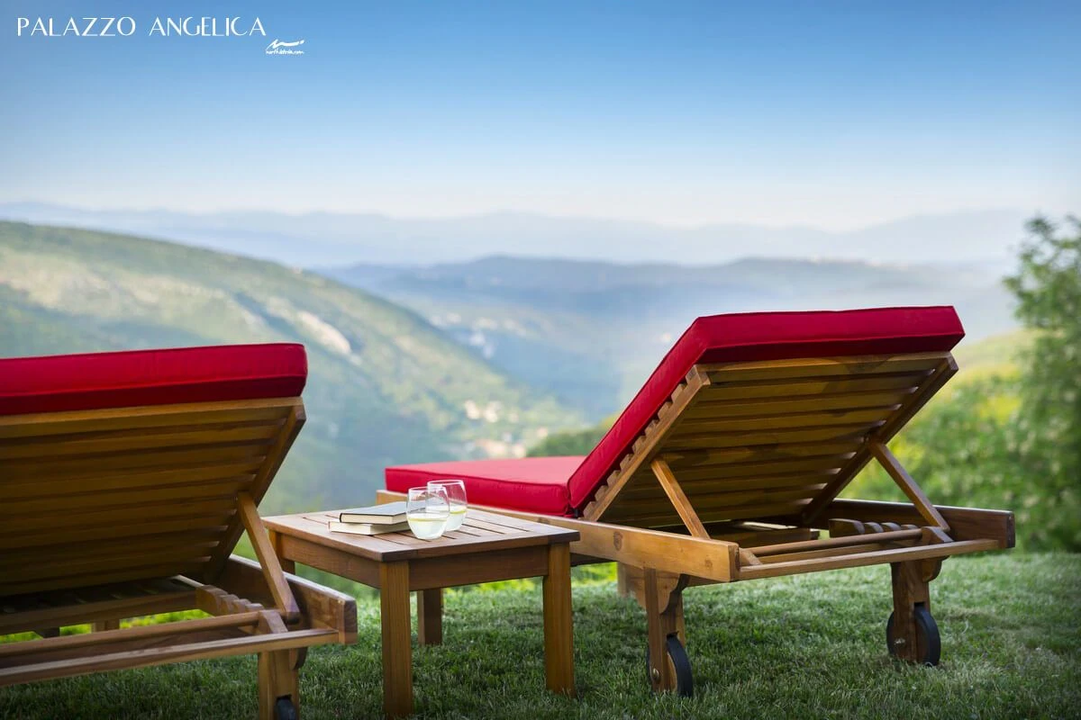 Palazzo Angelica red sun loungers overlooking a misty valley