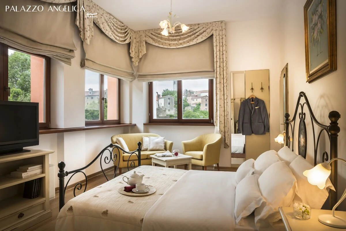 Palazzo Angelica bedroom with iron bed and draped curtains