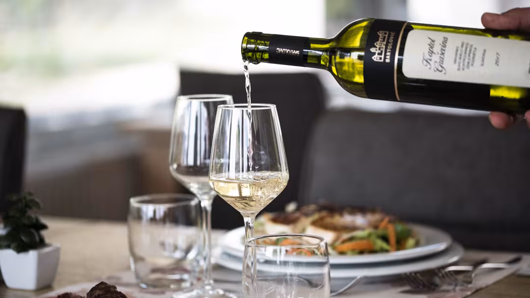 Oreskovic Guest House white wine being poured beside a plated meal
