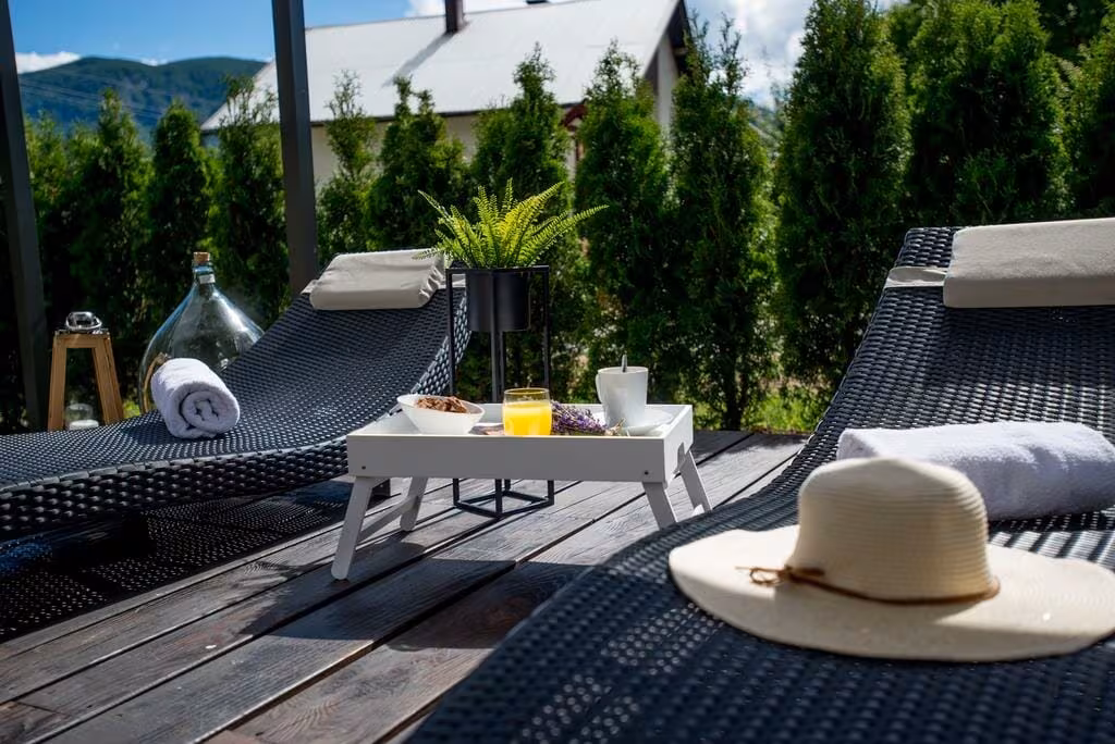 Oreskovic Guest House deck with loungers and straw hat beside a hedge