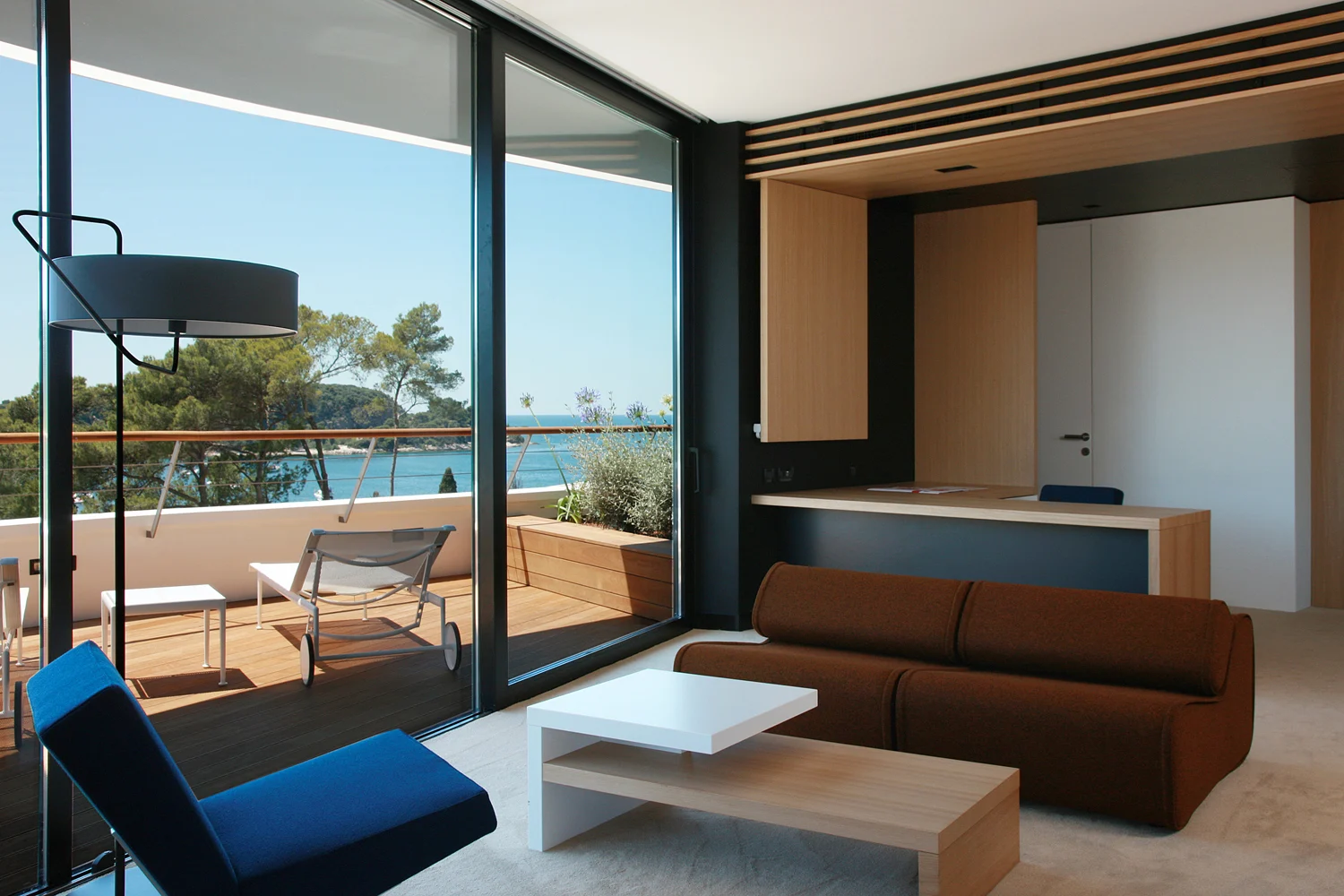 Lone suite with brown sofa and glass wall facing the sea