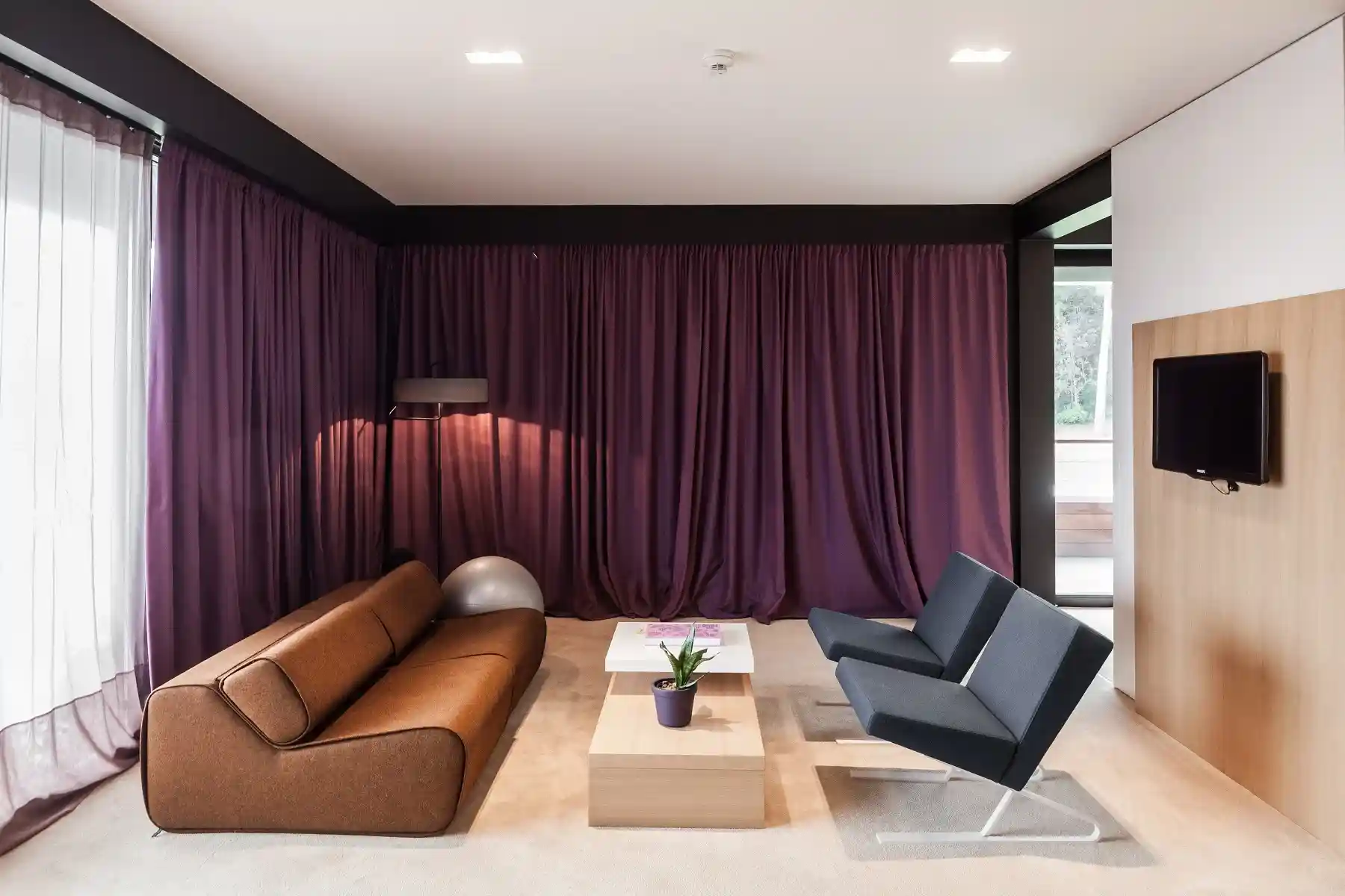 Lone lounge with purple curtains and brown leather sofa