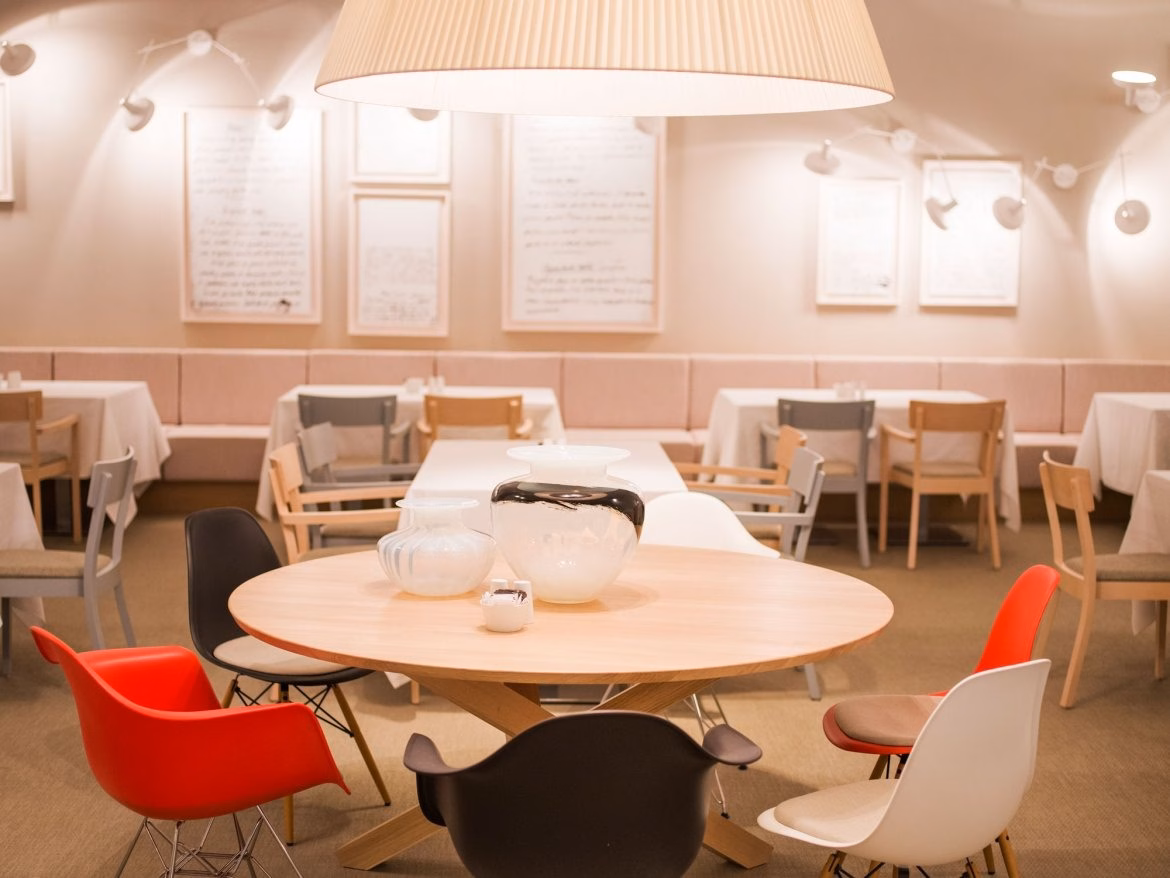 Kompas Hotel restaurant with round tables, white chairs and red accents