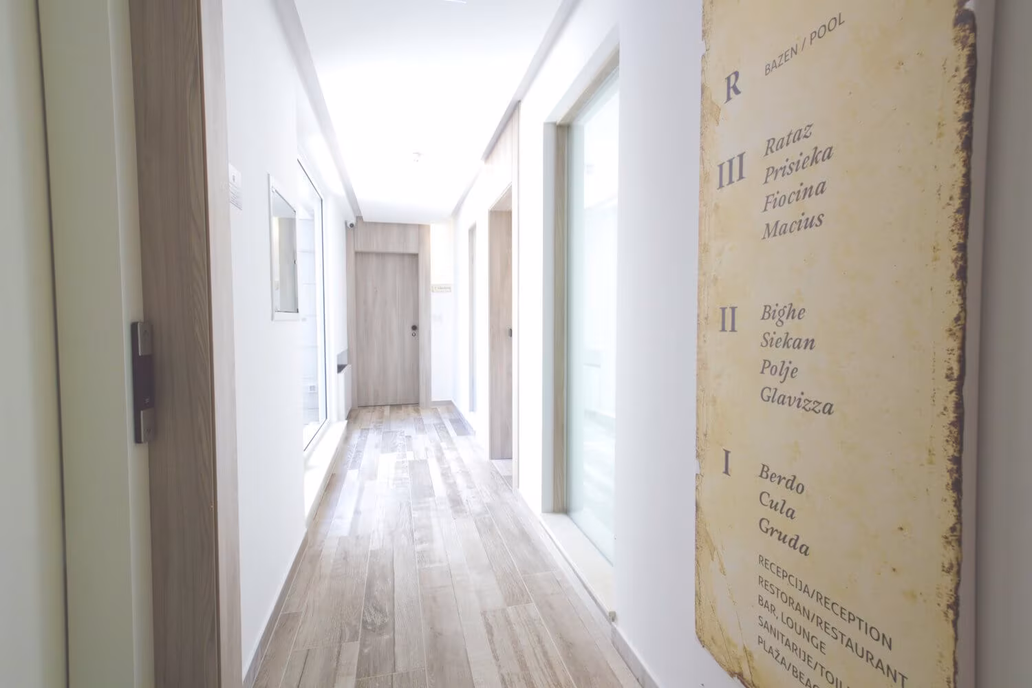 Kalamota Beach House white corridor with room doors and lettering on the wall