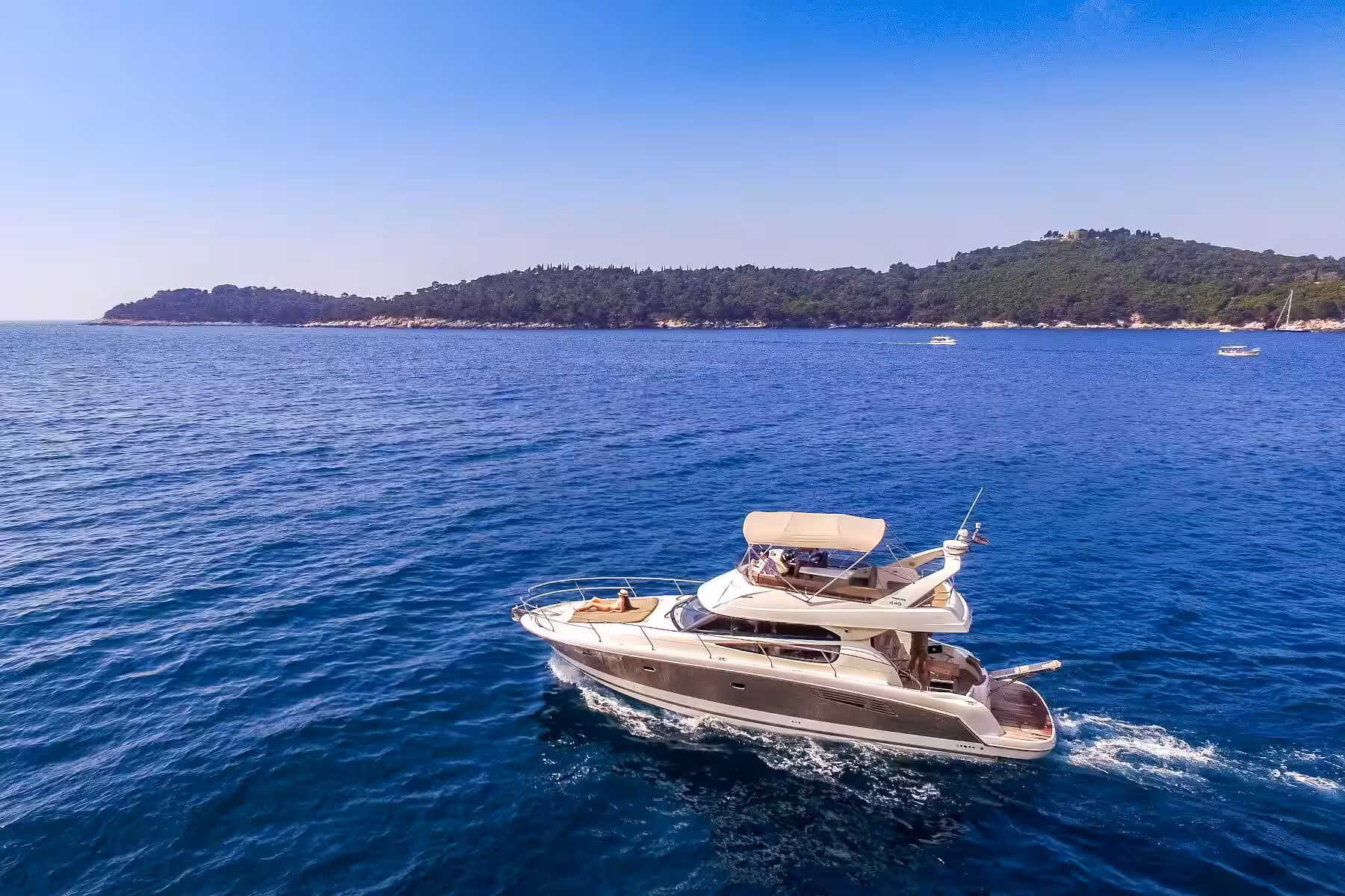 Kalamota Beach House motor yacht cruising on open sea near a wooded island
