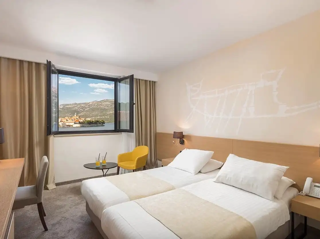 Hotel Liburna twin room with yellow chair and harbour view