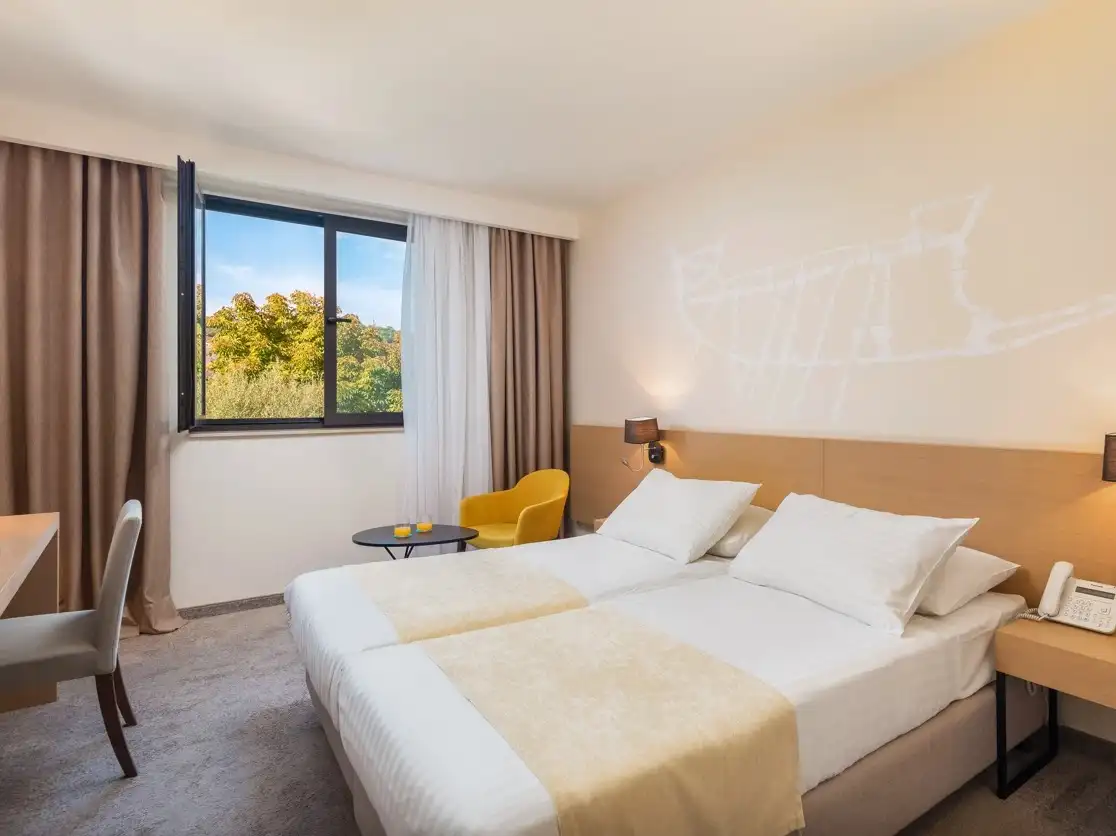 Hotel Liburna twin room with yellow chair and window onto greenery