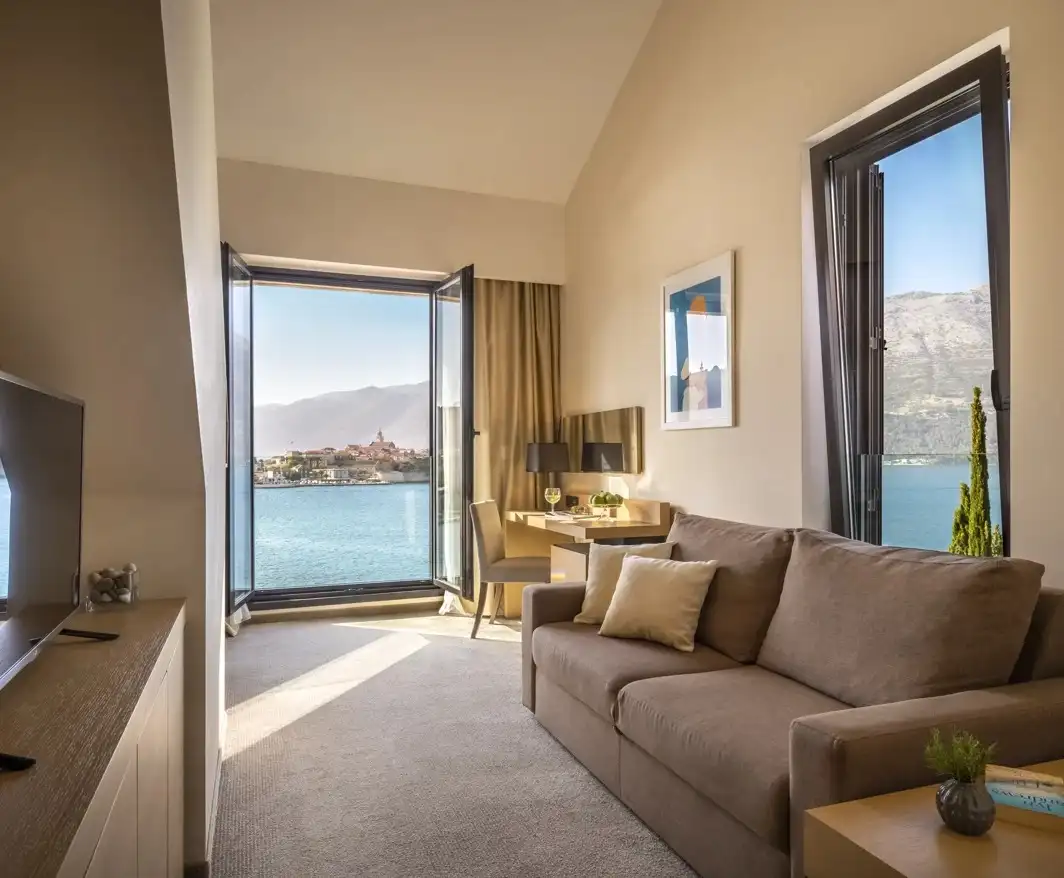 Hotel Liburna sitting room with sofa and balcony view across the water to the old town