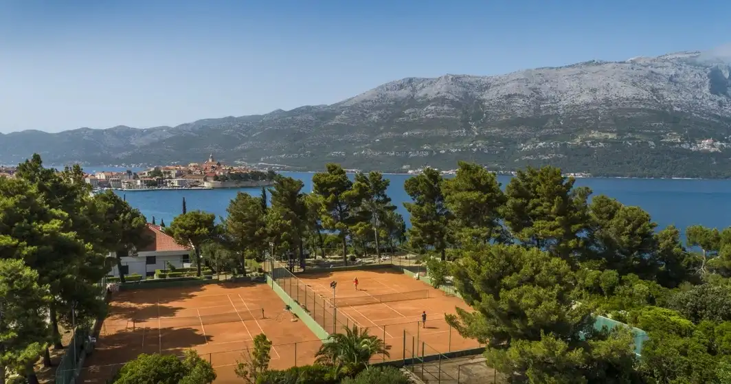 Hotel Liburna tennis courts among pine trees with the old town across the bay