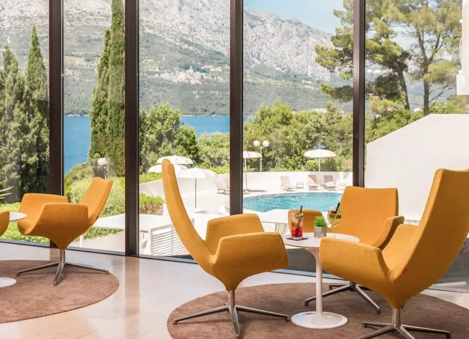 Hotel Liburna lounge with orange armchairs and floor-to-ceiling windows onto the pool