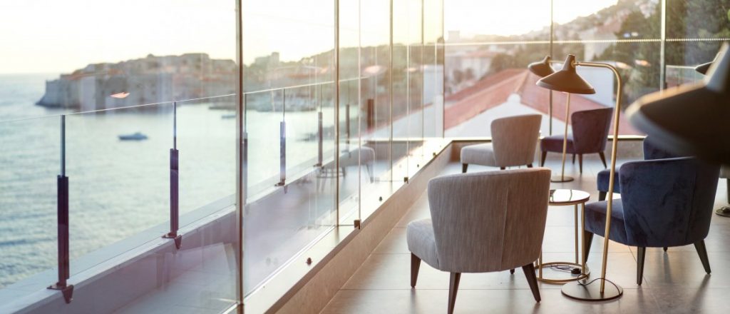 Hotel Excelsior glass-walled terrace with armchair overlooking the sea