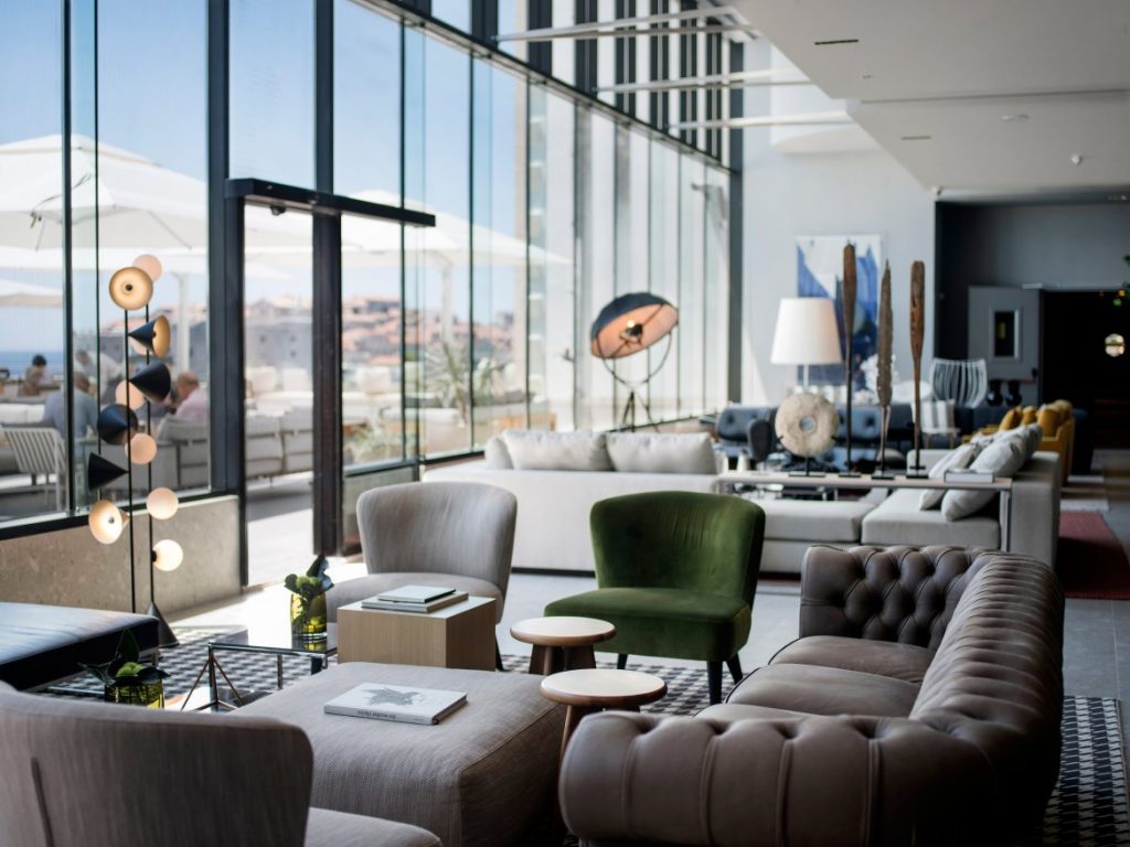 Hotel Excelsior lounge with chesterfield sofa, green armchair and tall windows