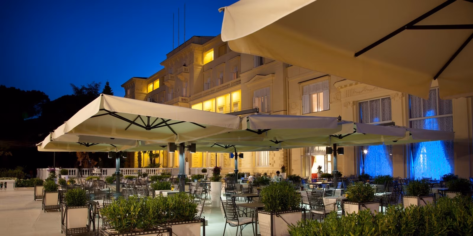 Hotel Kvarner terrace with parasols and illuminated facade at dusk