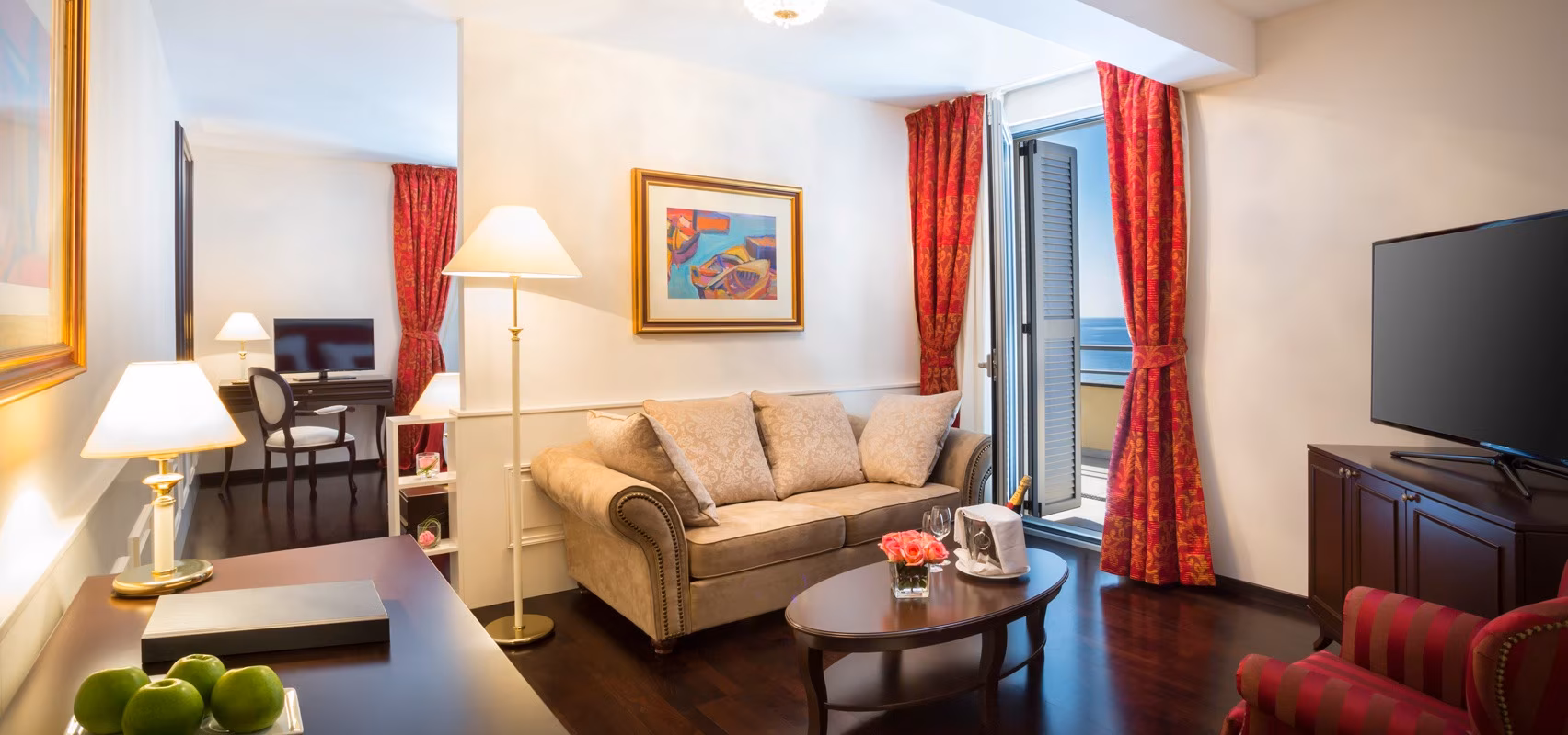 Hotel Kvarner sitting room with beige sofa, red curtains and painting
