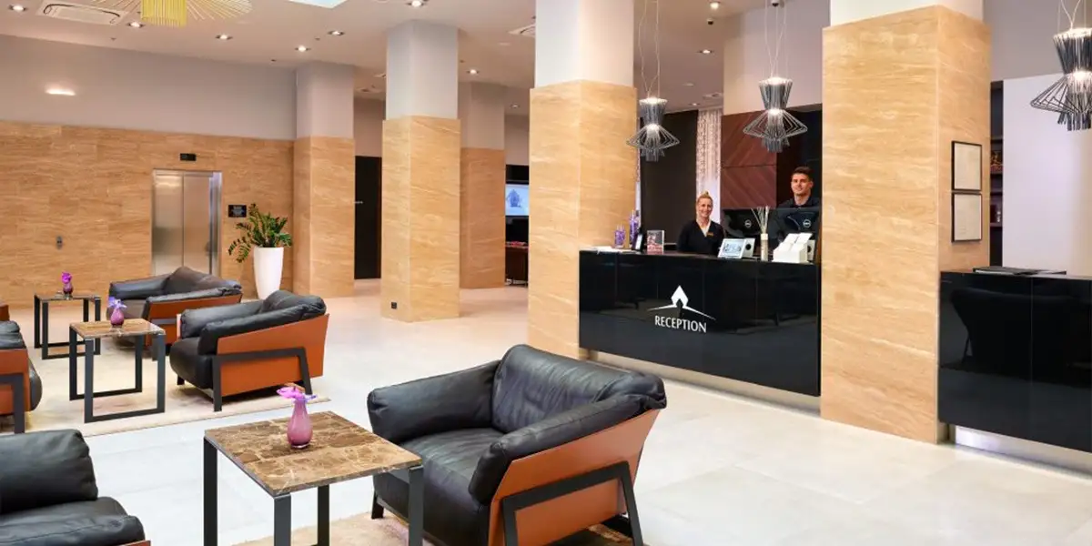 Hotel Cornaro reception desk with grey armchairs and wood-clad pillars