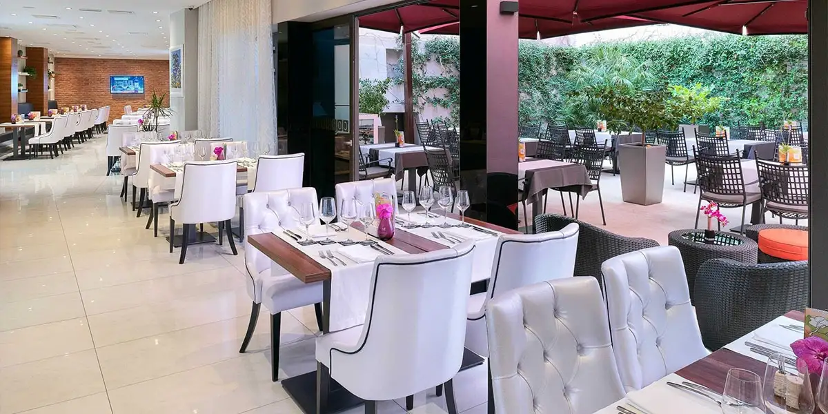 Hotel Cornaro terrace restaurant with white tufted chairs and red awning