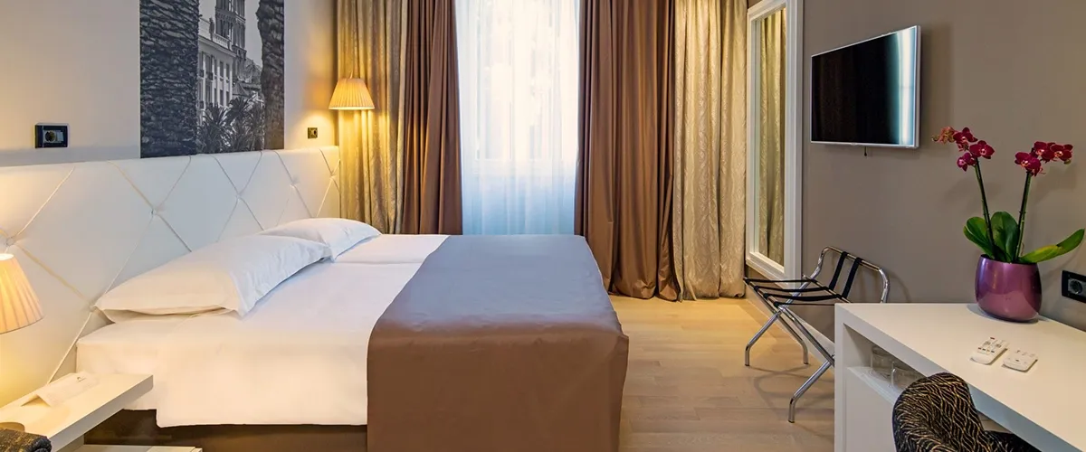 Hotel Cornaro double bedroom with tall curtains and bedside lamp