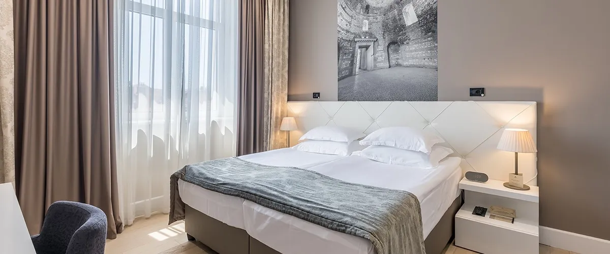 Hotel Cornaro double bedroom with grey throw and black-and-white archway photo