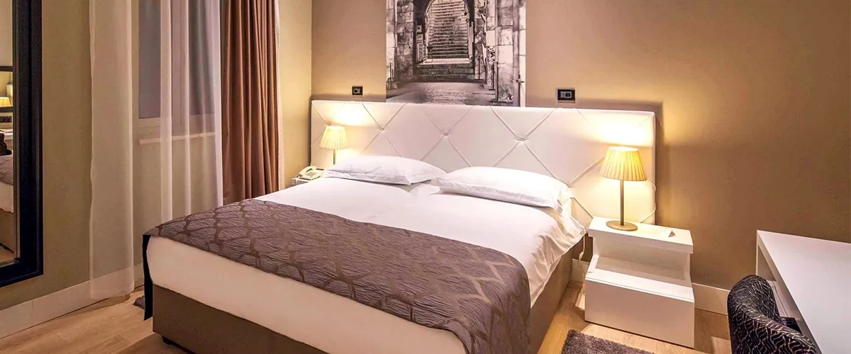 Hotel Cornaro double bedroom with padded headboard and stone street photo