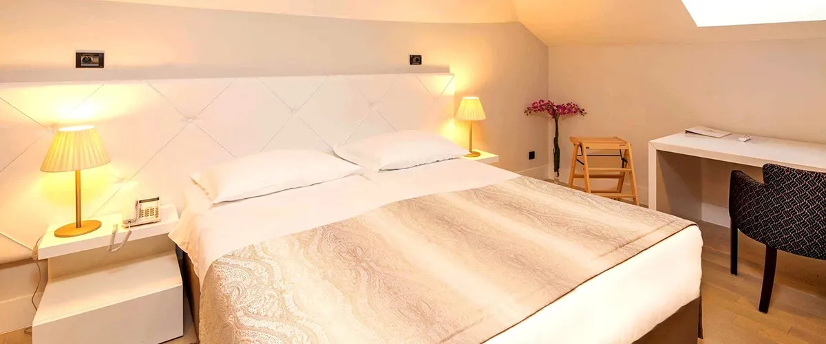Hotel Cornaro attic bedroom with white bedding and orchid