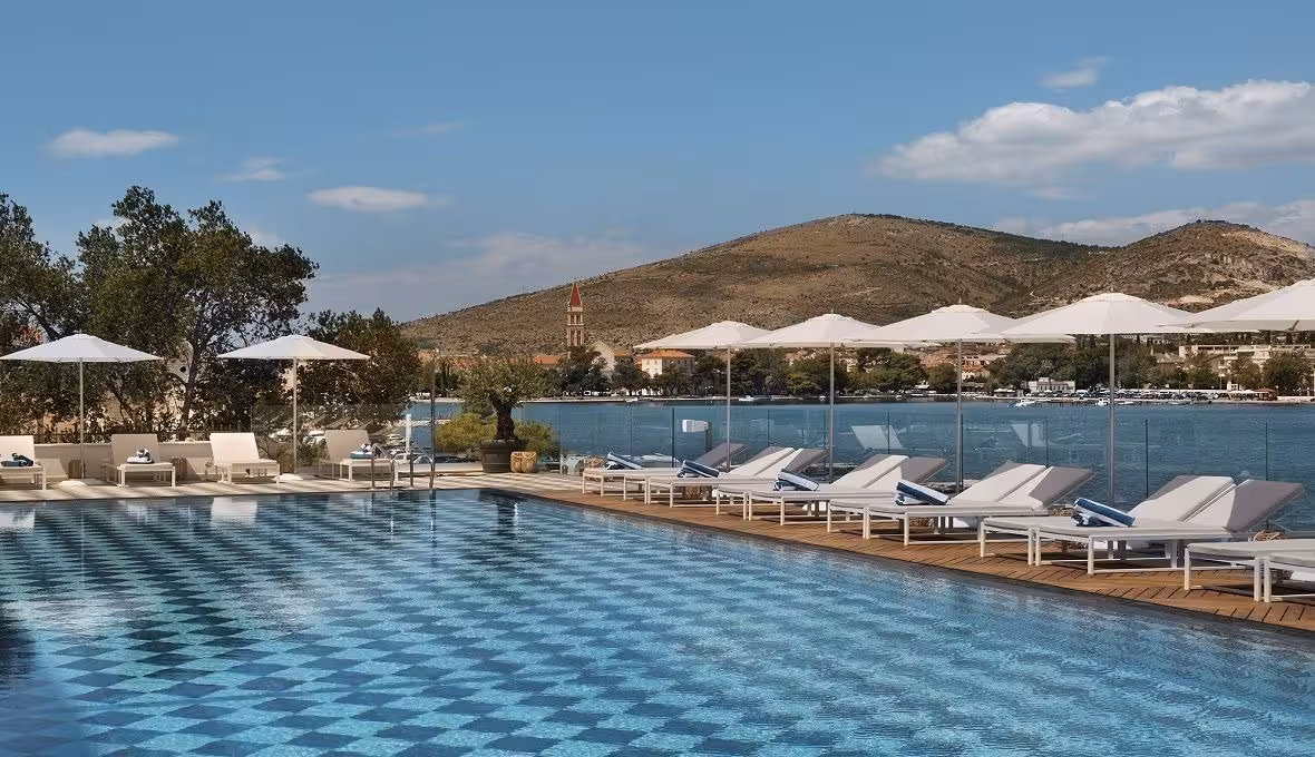 Brown Beach House Design Hotel outdoor pool with parasols facing the sea and hills