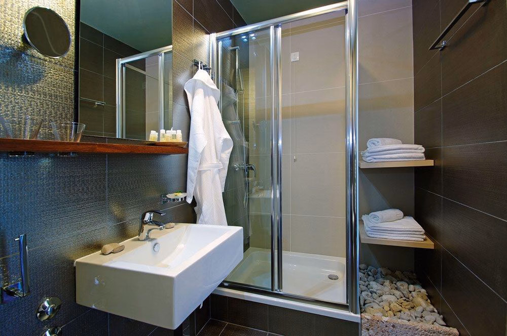 Boutique Hotel Bol dark tiled bathroom with glass shower and bathrobe