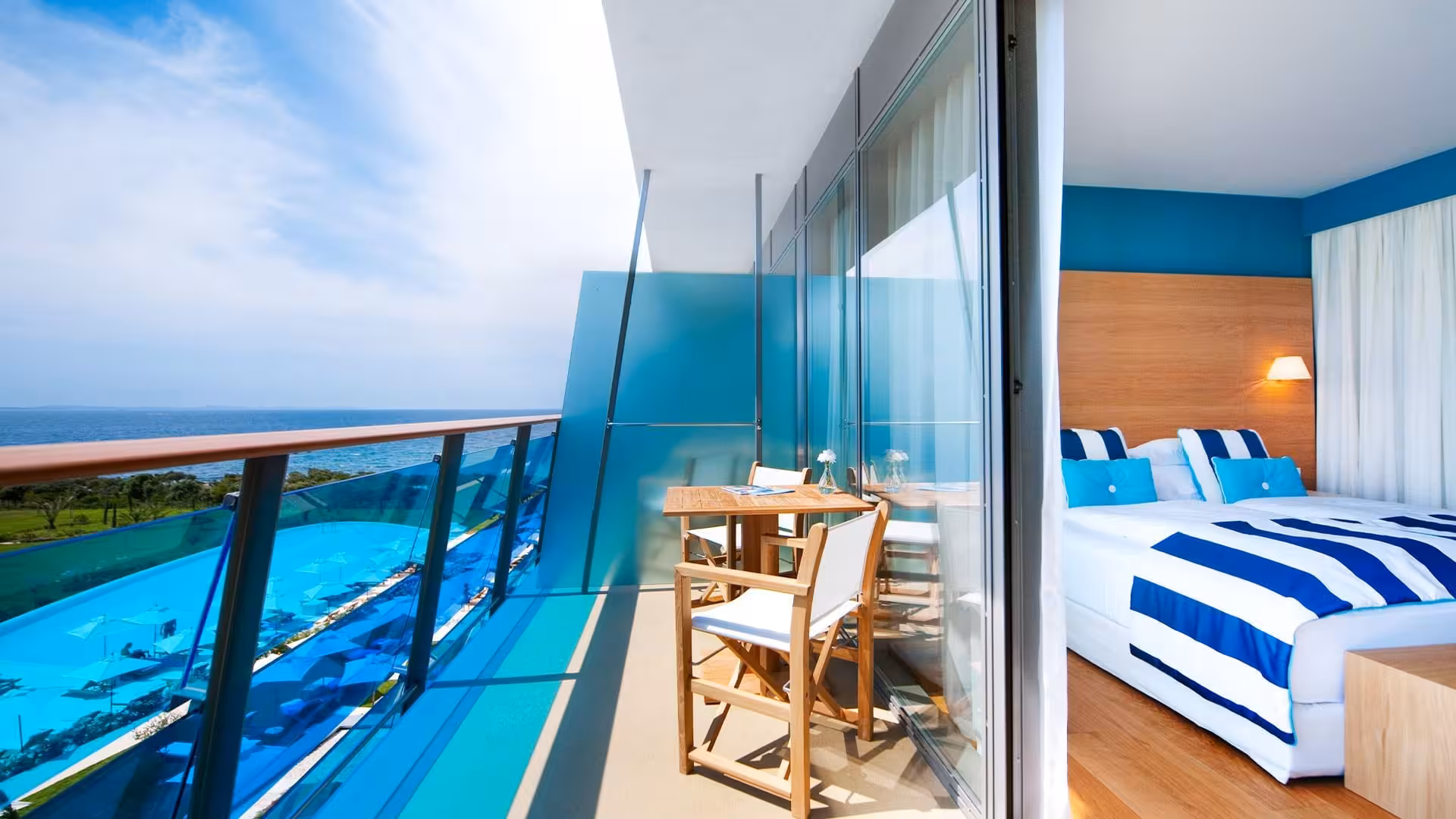 Falkensteiner Hotels Iadera/Senia Apartments bedroom with striped bedding and glass balcony over the sea