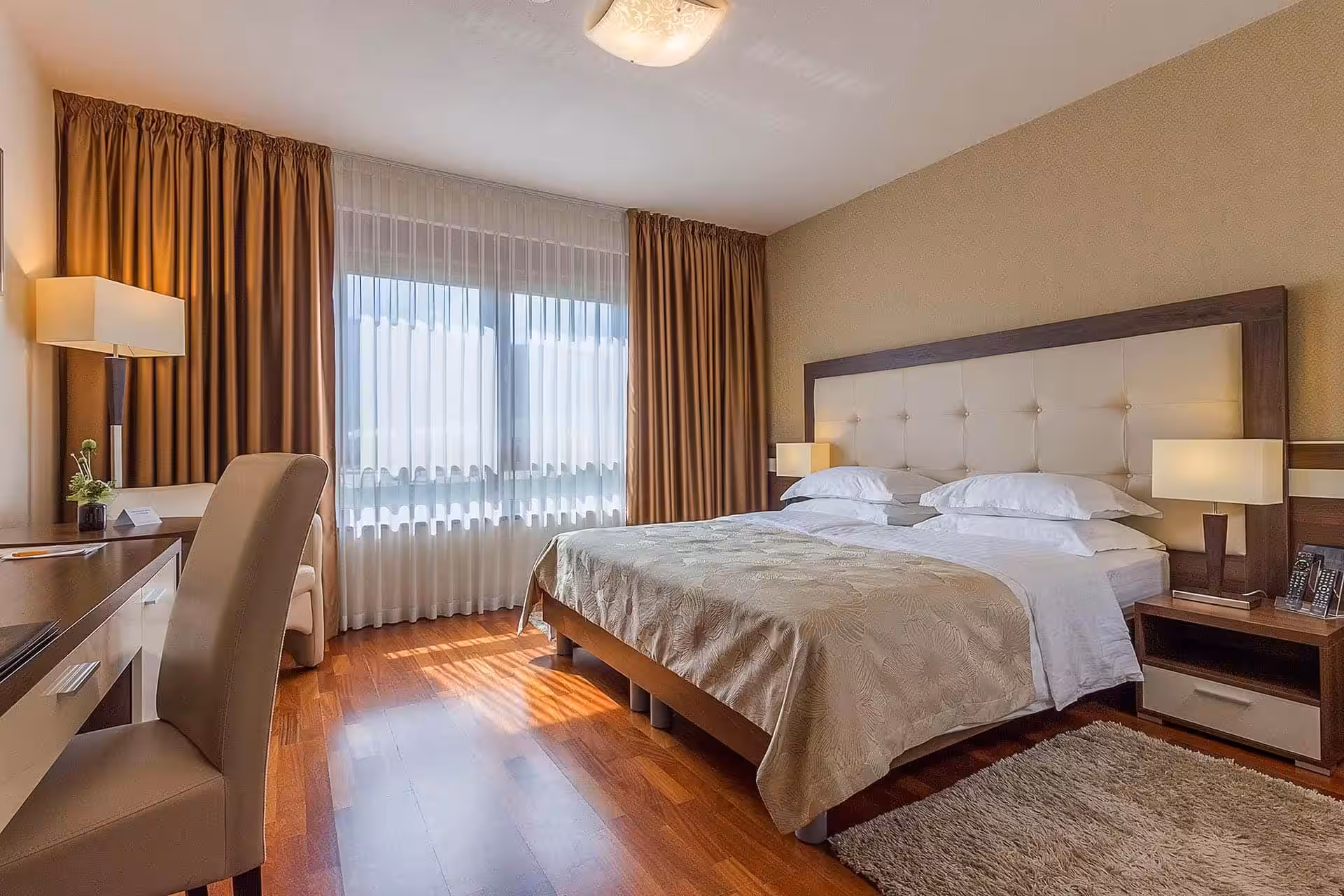 Degenija Hotel bedroom with tufted headboard and large window