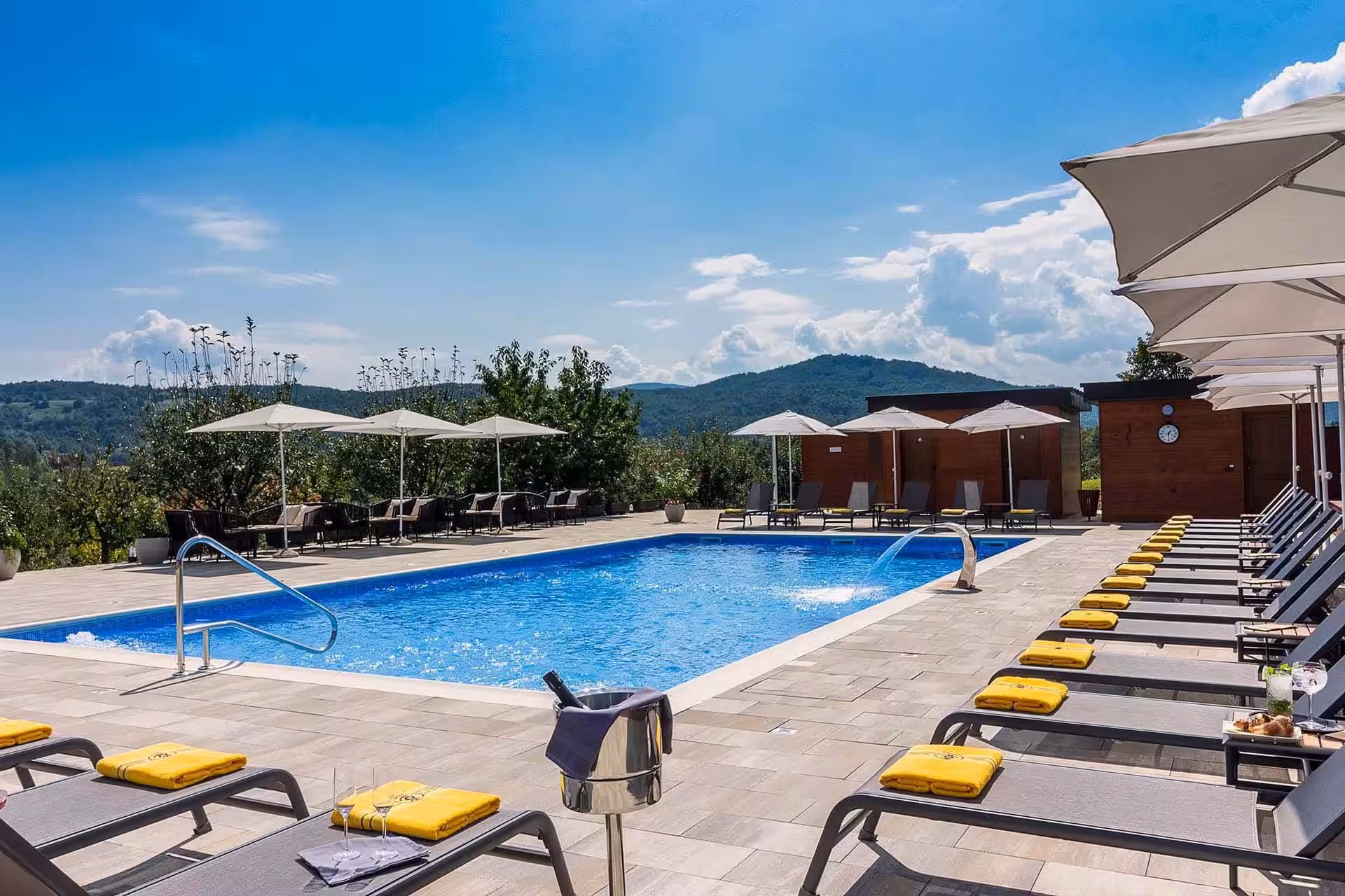 Degenija Hotel outdoor pool with yellow loungers and hills behind