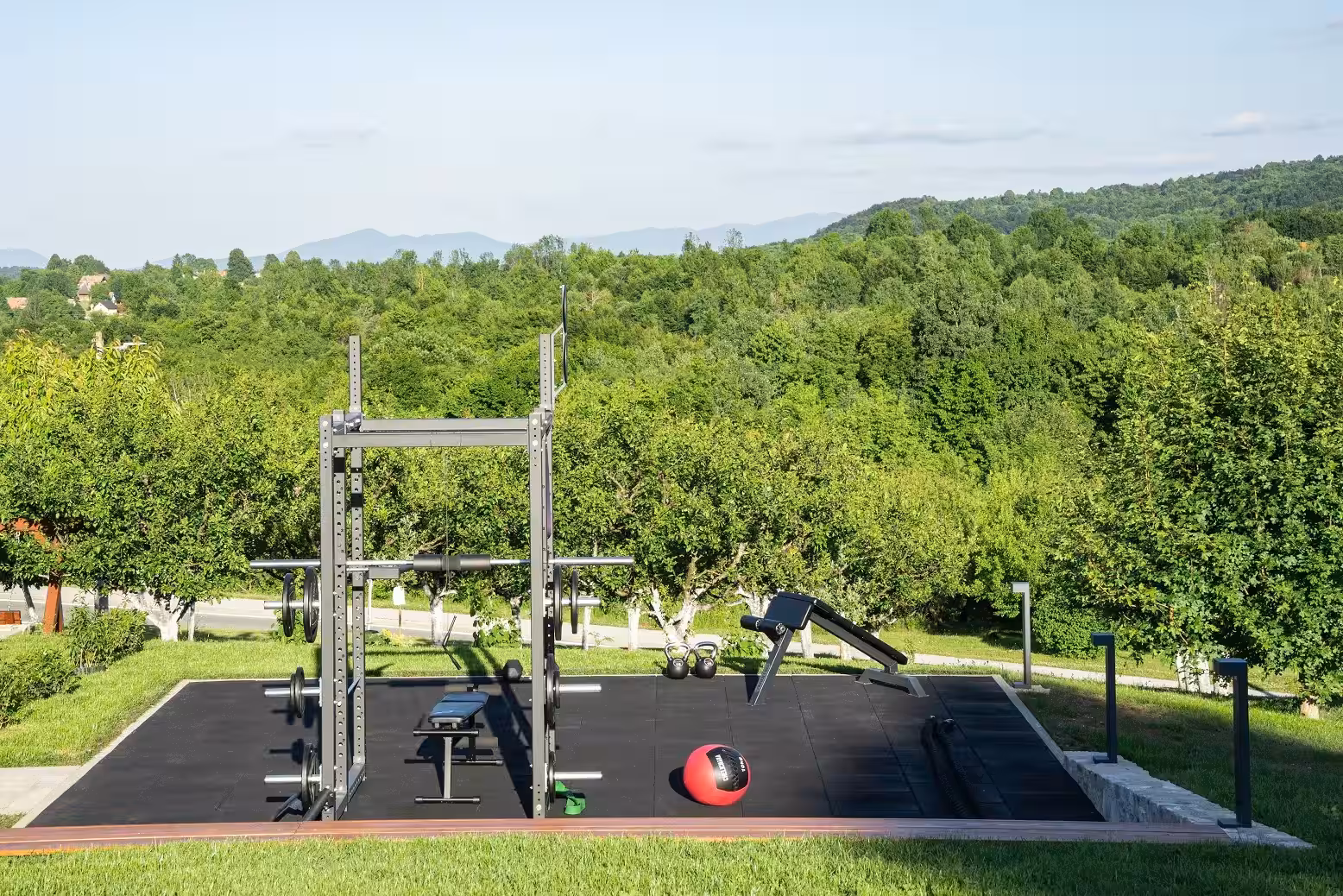 Degenija Hotel outdoor fitness equipment on a lawn with trees