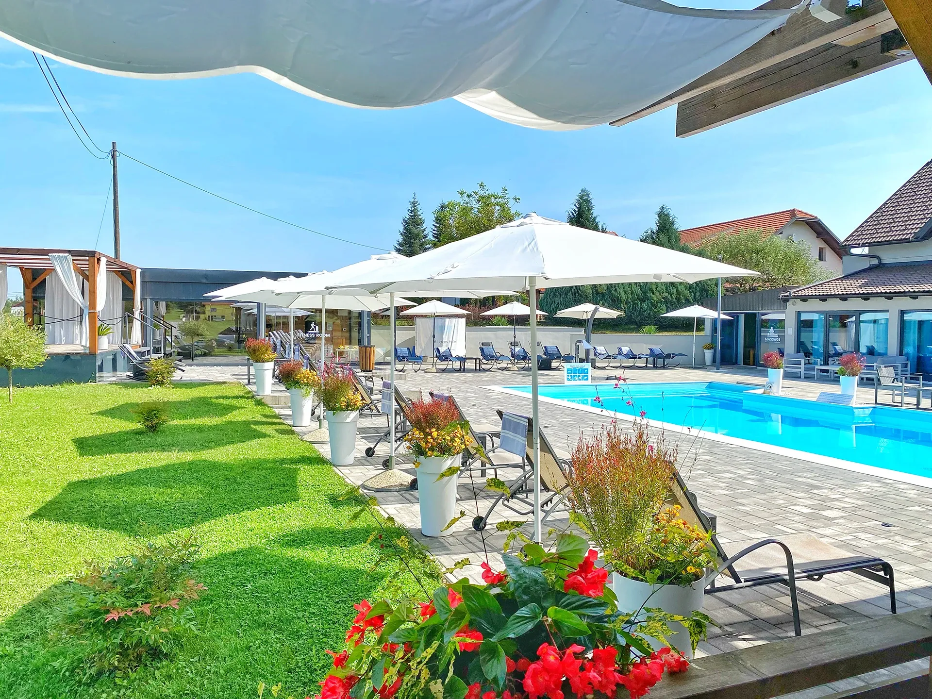 16 Lakes garden lawn with flower beds and parasols beside the pool