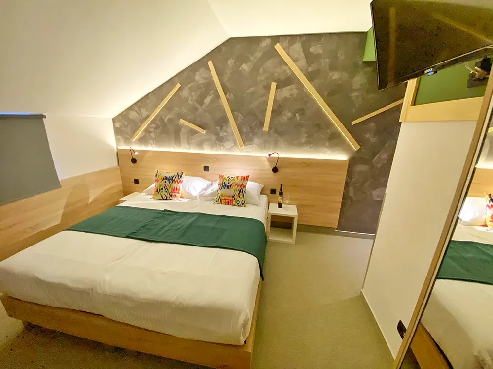 16 Lakes attic double bedroom with green throw and geometric wooden wall