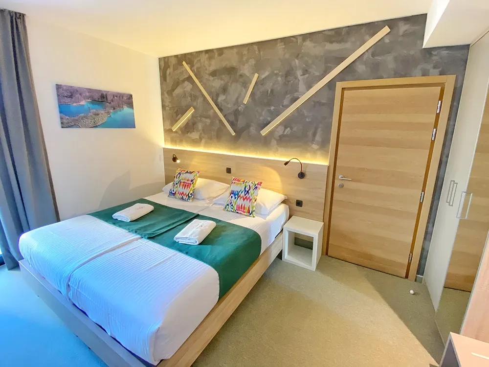 16 Lakes double bedroom with teal throw and geometric wooden wall design