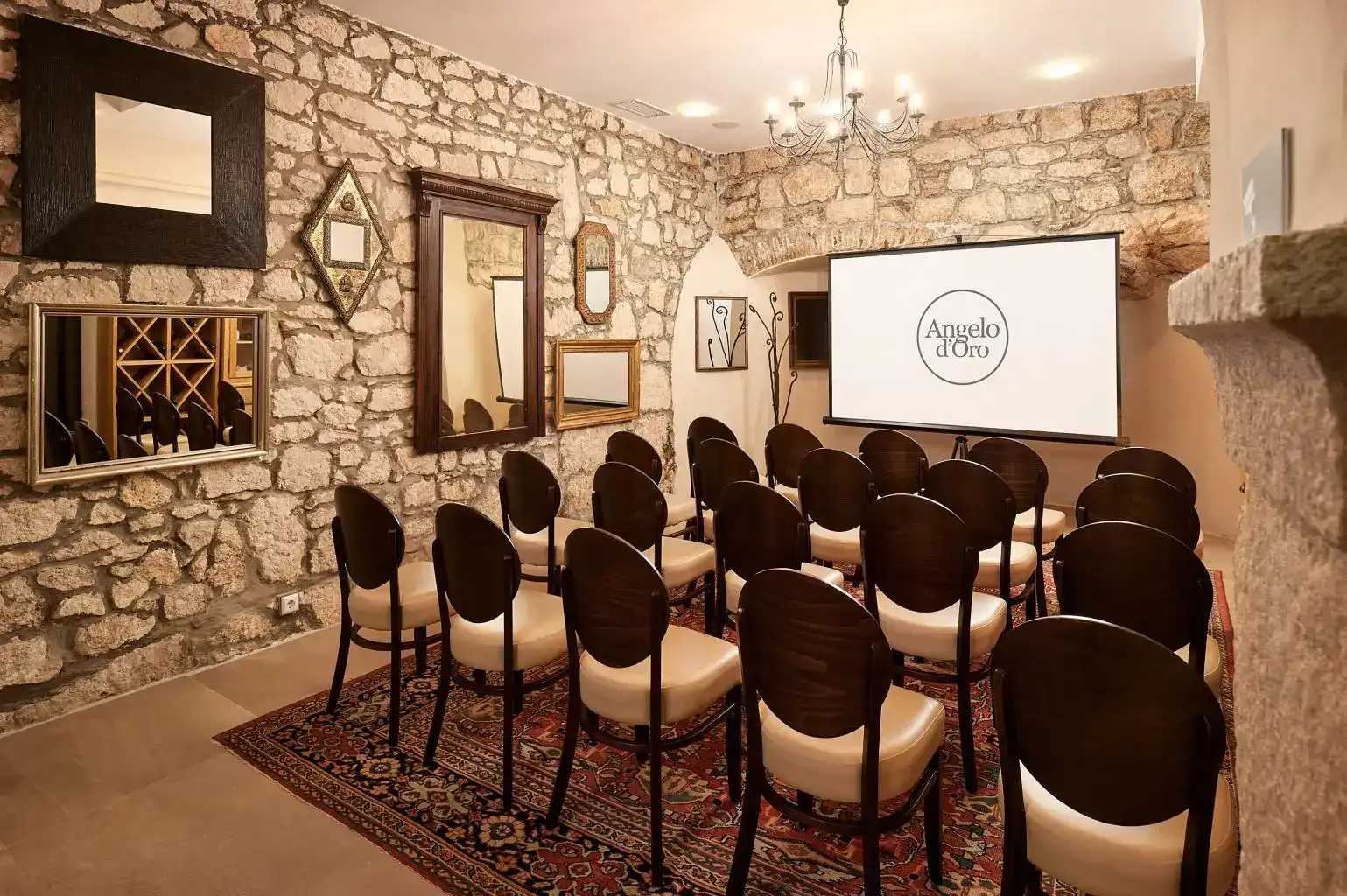 Angelo d'Oro meeting room with stone walls, rows of chairs and screen