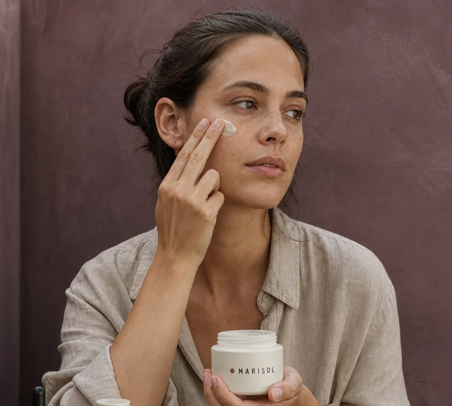 Woman applying Marisol cream to her cheek