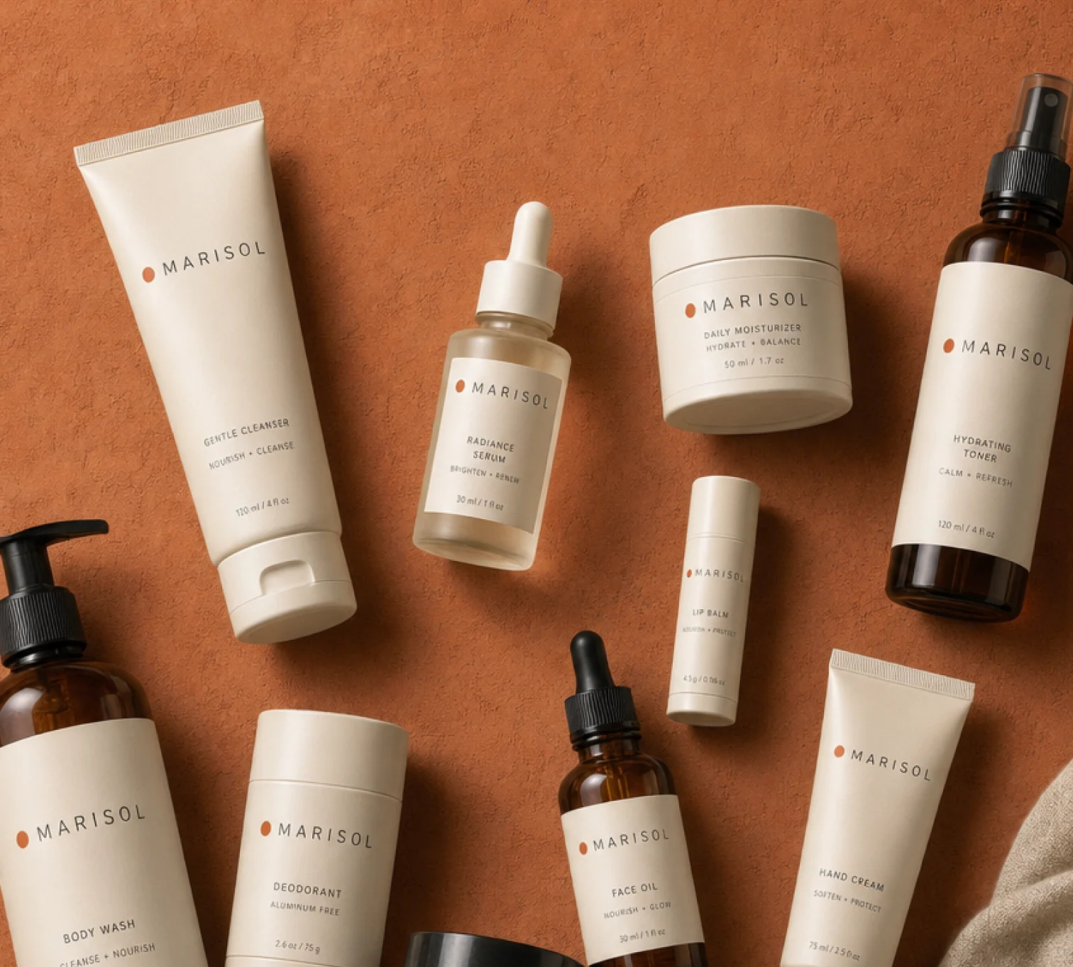 Marisol cleanser, body wash, serum and cream bottles on a terracotta surface