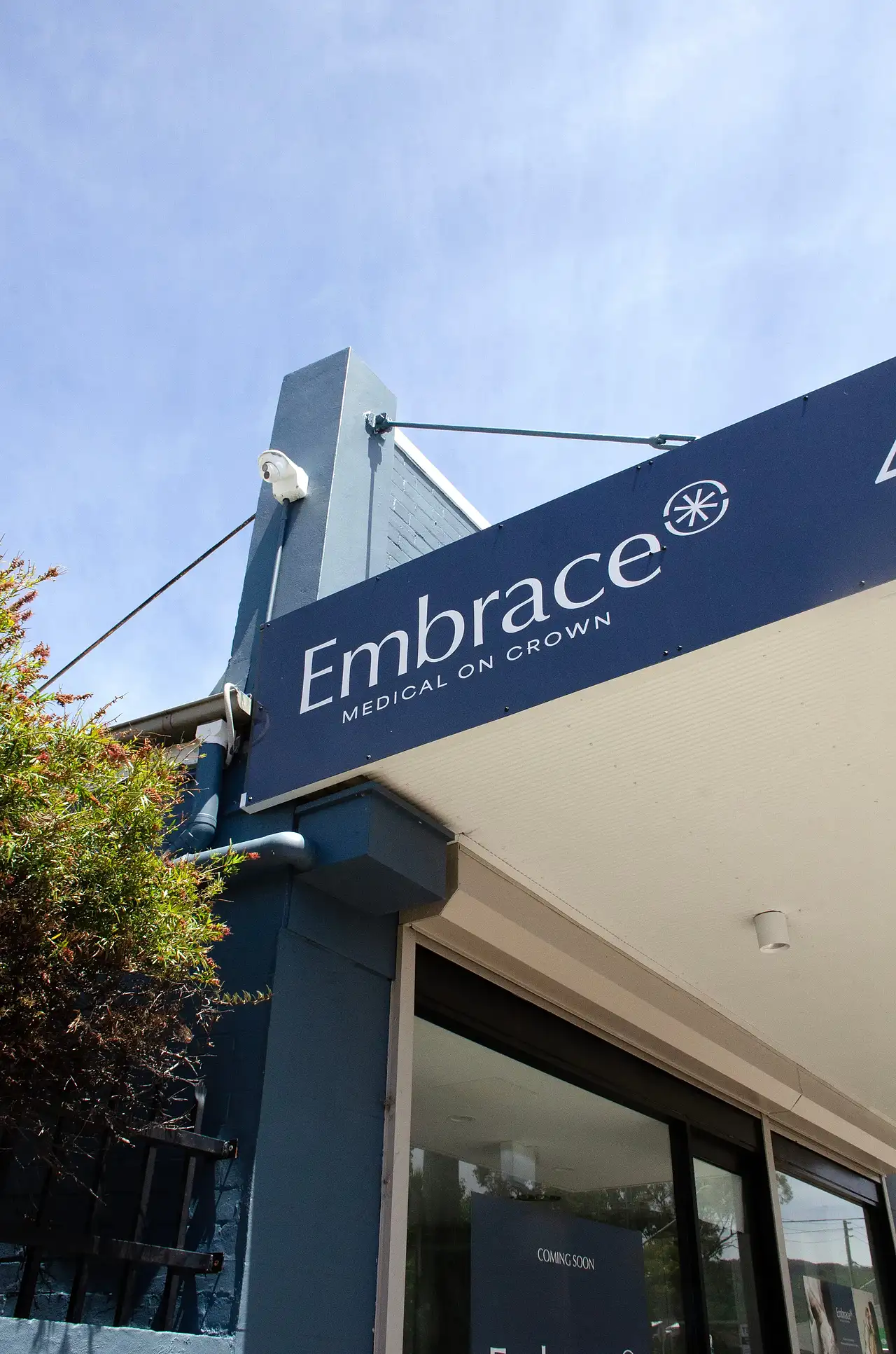 Blue building facade with a sign reading 'Embrace Medical on Crown' against a clear sky.