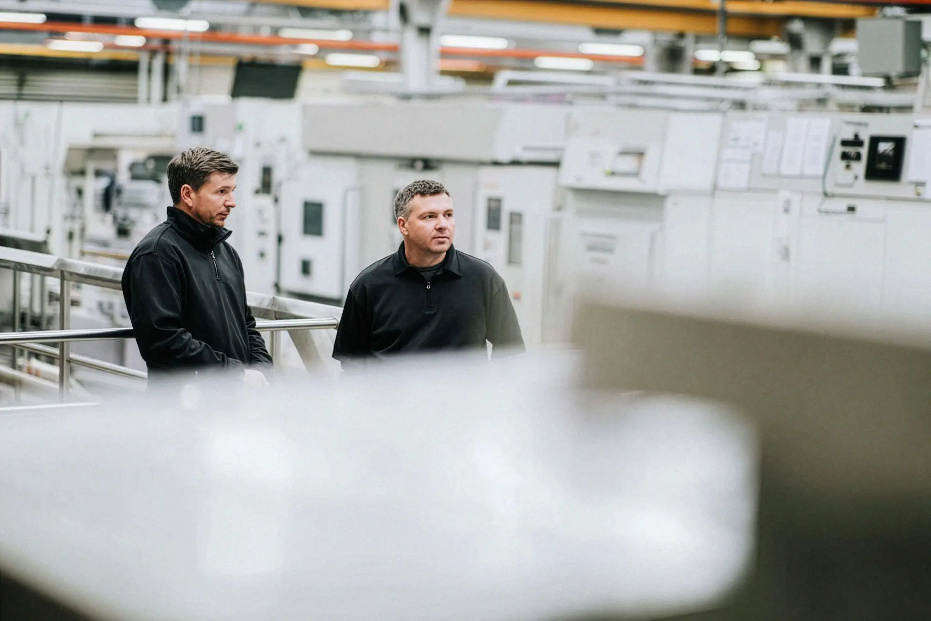 Zwei Servicetechniker von Averon Technologies stehen in einer modernen Industriehalle und besprechen die Wartung und Integration industrieller Energiesysteme.