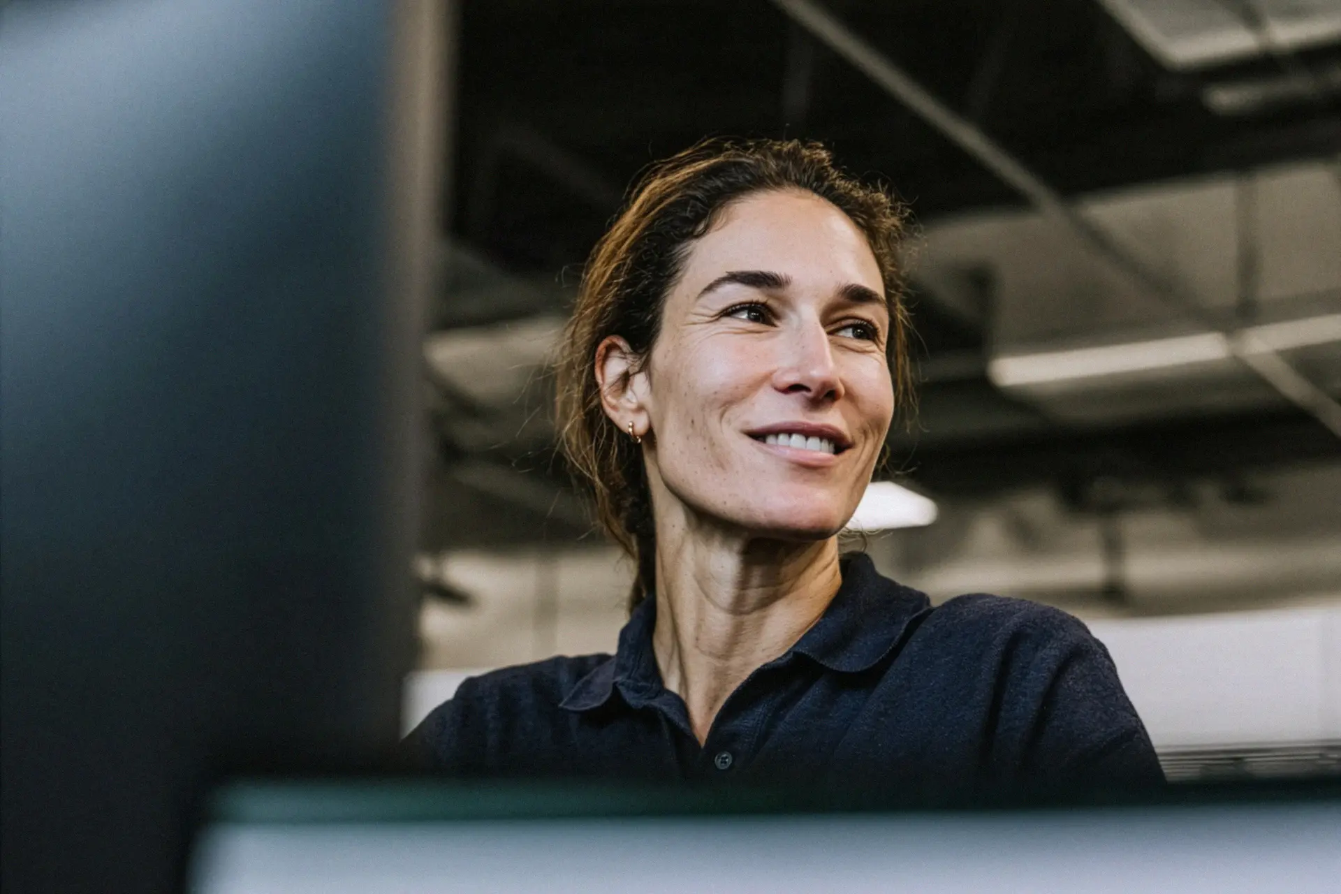 Lächelnde Mitarbeiterin in einer modernen Industriehalle von Averon Technologies – authentischer Einblick ins Arbeitsumfeld und Teamkultur.