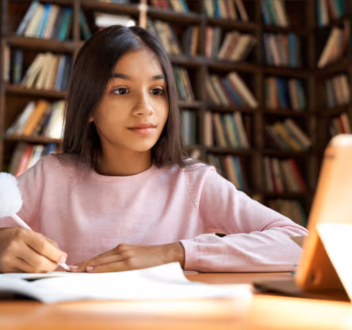 Child focused on screen, writing in notebook for Independent Educational Evaluation (IEE). 