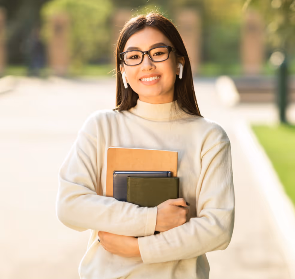 Girl smiling outside, holding books after college accommodations evaluation.