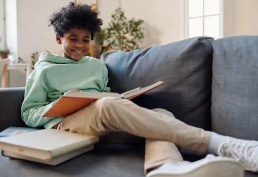 Child focused on screen, writing in notebook for Independent Educational Evaluation (IEE). 