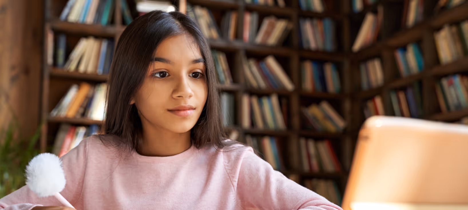 Child focused on screen, writing in notebook for Independent Educational Evaluation (IEE).