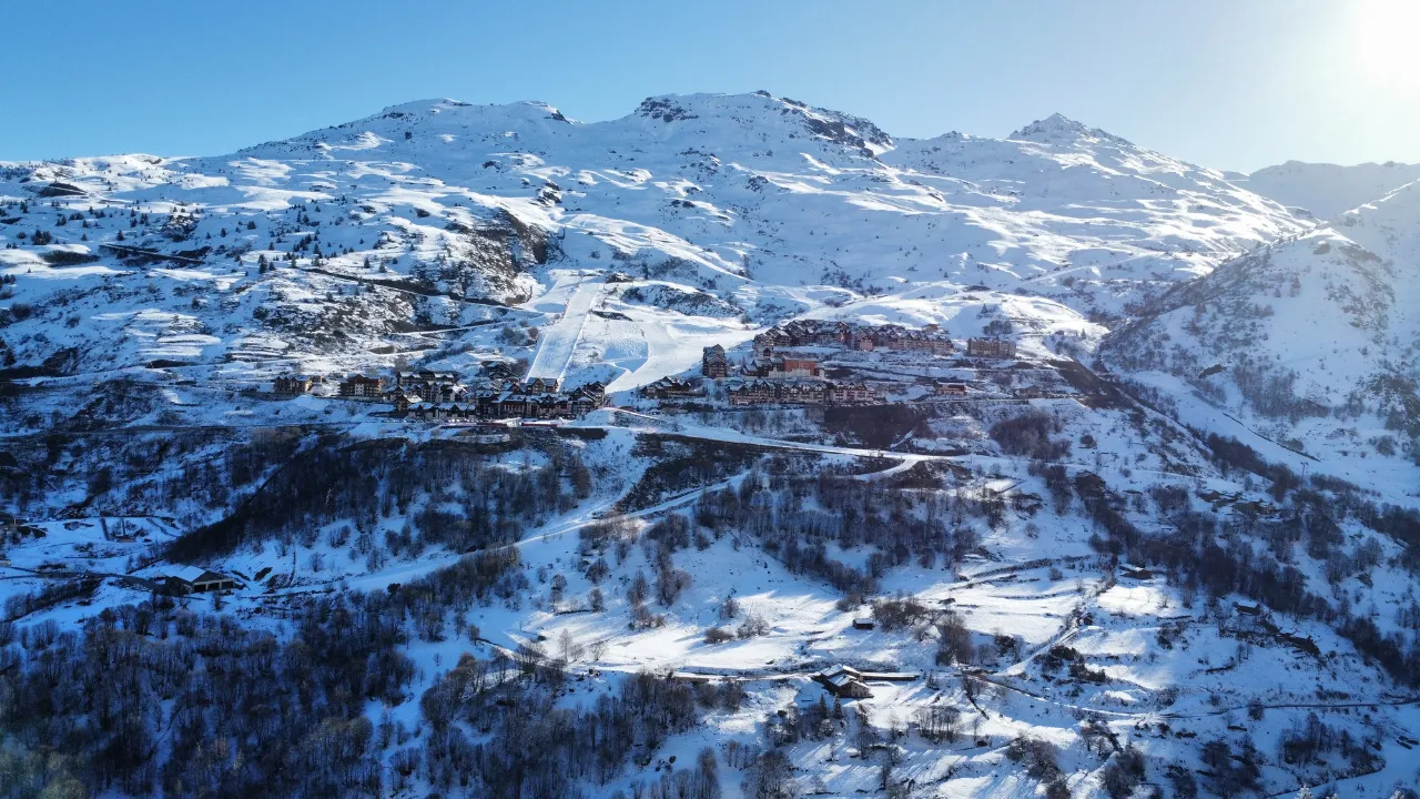 Paysage montagneux enneigé de Valmeinier au pied des sommets sous un ciel bleu clair.