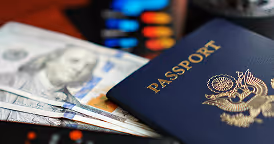 Close-up of a United States passport and US dollar bills on a table.